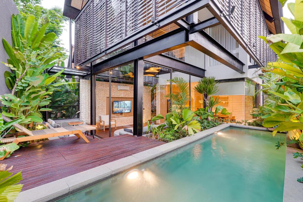 een binnenzwembad in een huis met een houten terras bij Luxury 5BR Villa Byrdland Pasisi - Canggu in Canggu
