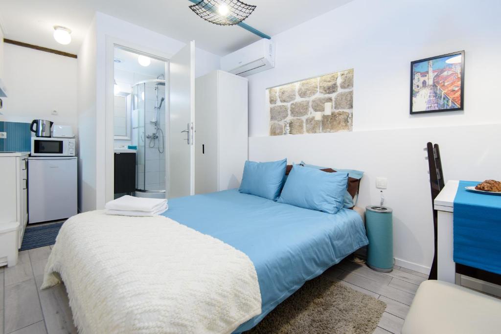 1 dormitorio con 1 cama azul y cocina en Artist Residence Dubrovnik, en Dubrovnik
