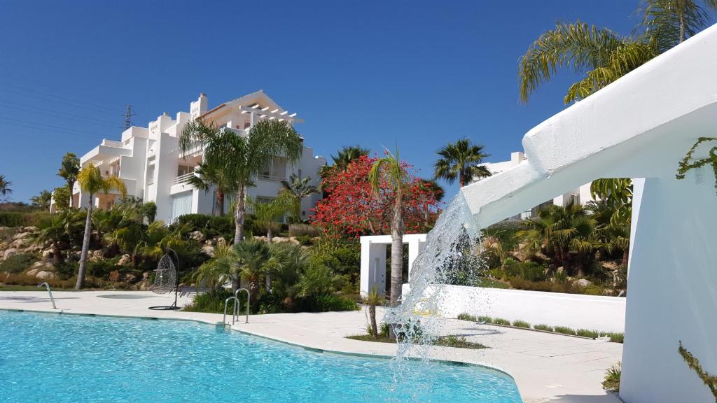 a swimming pool with a fountain in front of a building at Alcazaba Lagoon in Estepona