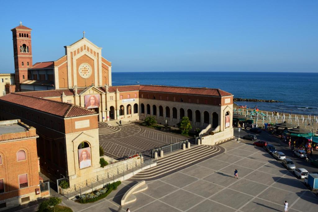 a large building with a clock tower next to the ocean at SWEET HOME & WELLNESS affittacamere in Nettuno