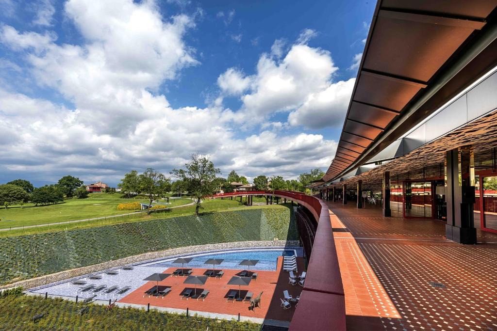 een uitzicht op een gebouw met een zwembad en een veld bij Villaverde Hotel Spa&Golf Udine in Fagagna