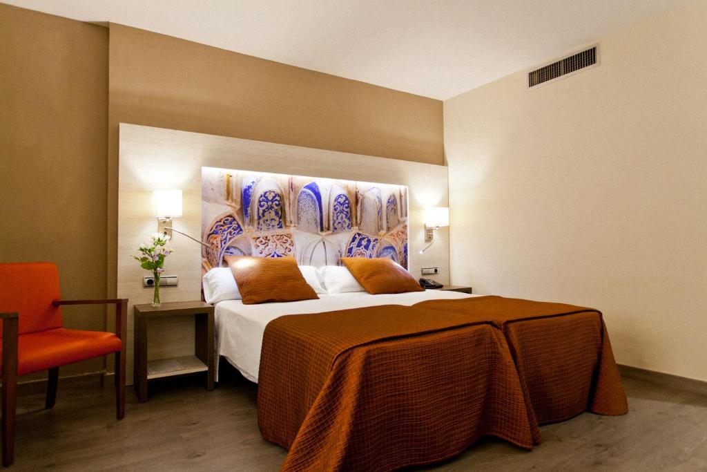 um quarto de hotel com uma cama e uma cadeira laranja em Porcel Sabica em Granada