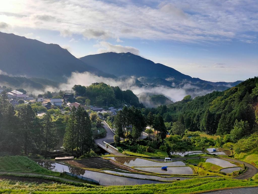 a town in a valley with mountains in the background at Homestay at Remote Organic Farm in Nachikatsuura