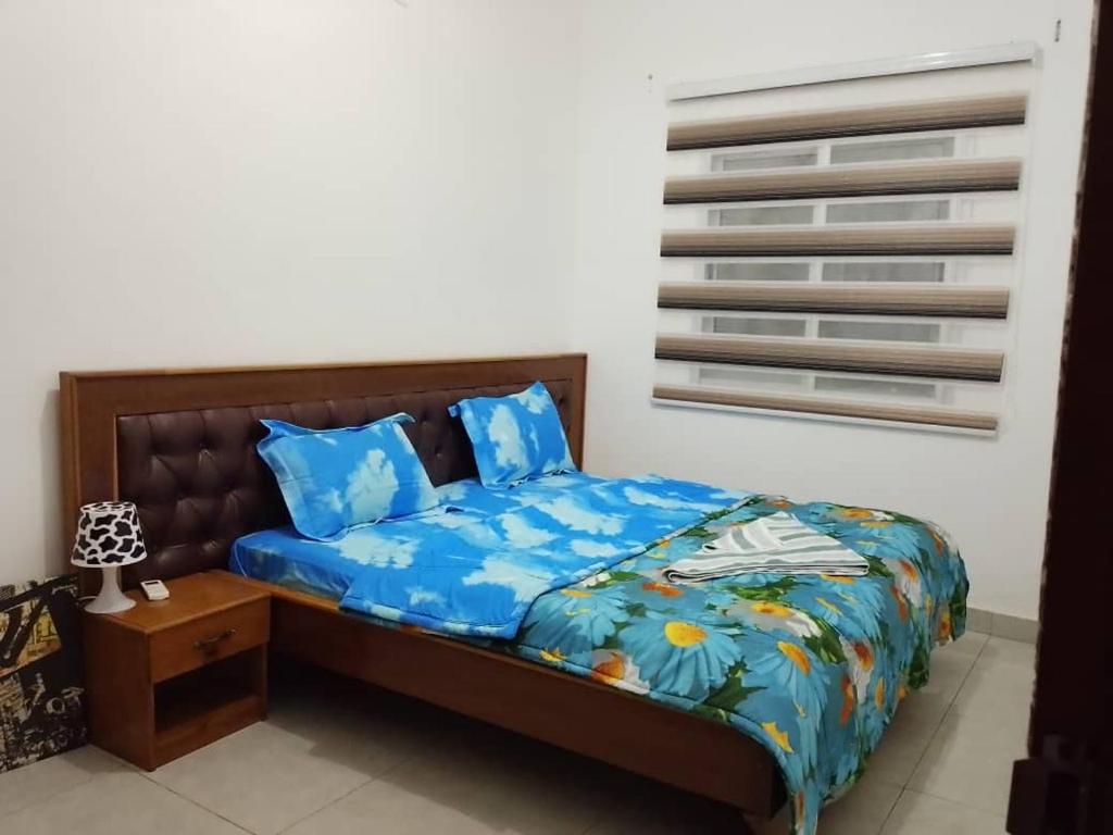 a bedroom with a bed with blue sheets and blue pillows at Aloha Suites Odza - by Skyline Residence Services in Yaoundé