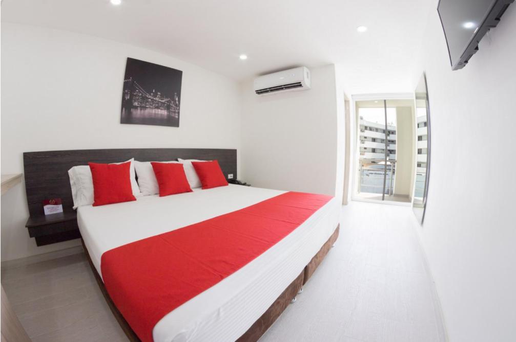 a bedroom with a large bed with red and white pillows at Massay Hotel in Neiva