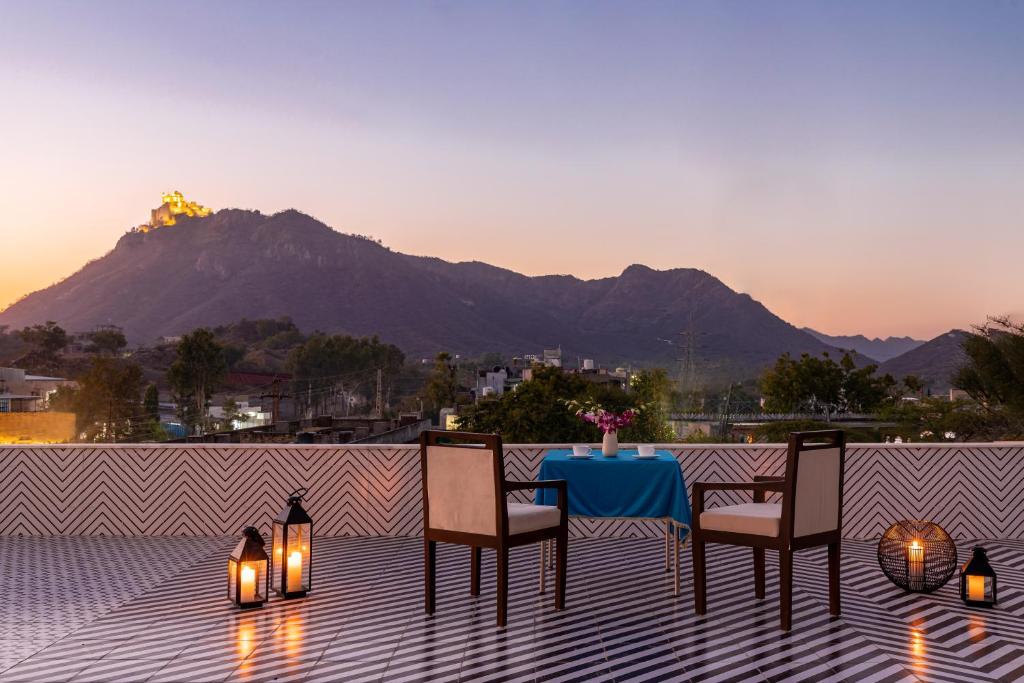 a table and chairs on a patio with a mountain in the background at Seasons - A Boutique Hotel-Nearby Biological Park in Udaipur