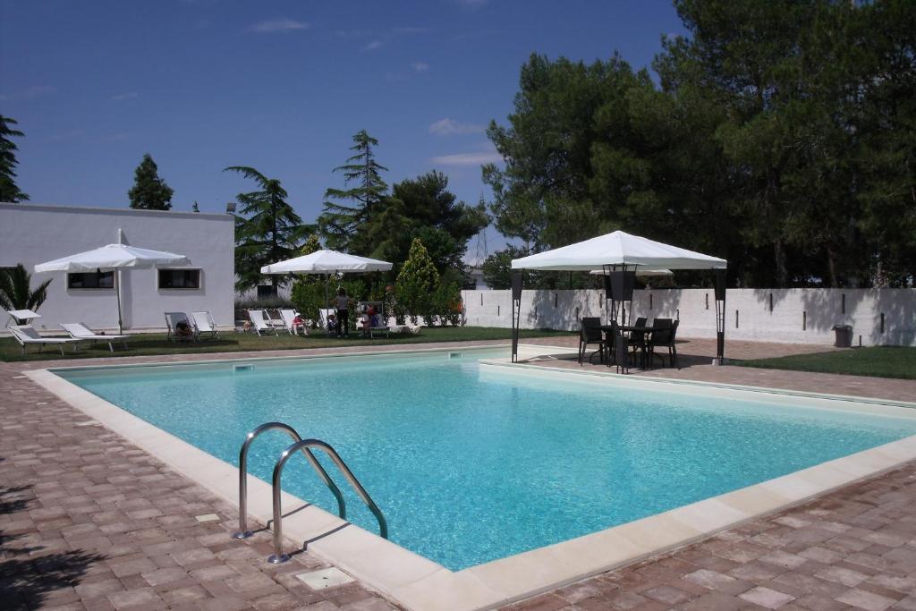 una piscina con sedie e ombrelloni accanto ad essa di La Ferula Bed&Pool a Santeramo in Colle