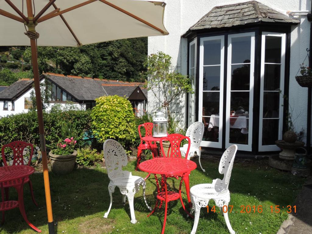 un grupo de sillas y mesas y una sombrilla en Orchard House Hotel, en Lynmouth