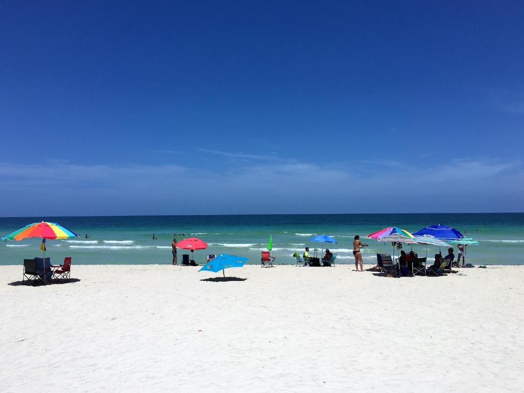 un grupo de personas sentadas bajo sombrillas en una playa en Oceanfront Studio Casablanca Miami Beach, en Miami Beach