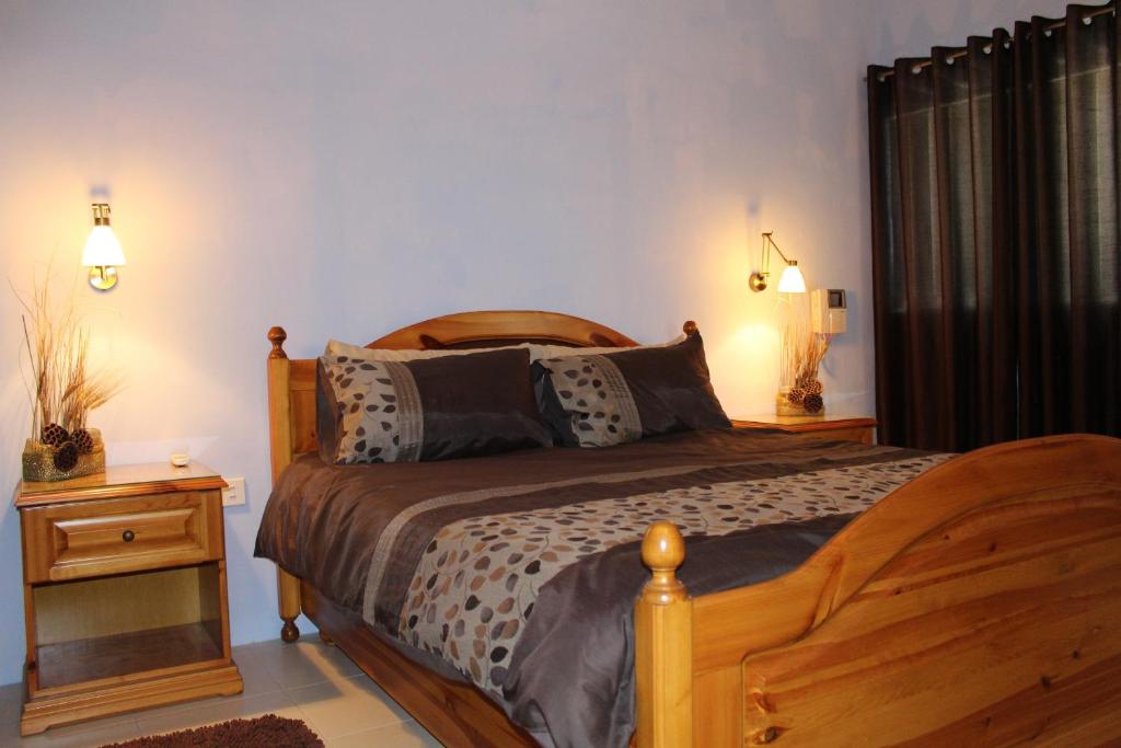 a bedroom with a wooden bed and a night stand at South Village Townhouse in Żabbar