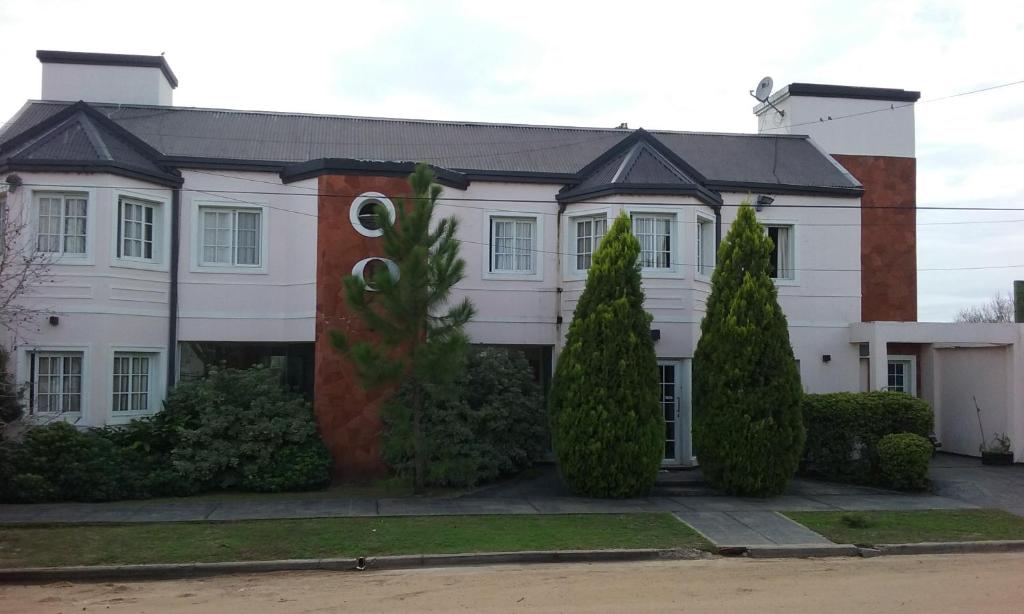 une maison blanche avec des arbres devant elle dans l'établissement Hotel Queguay, à Colón