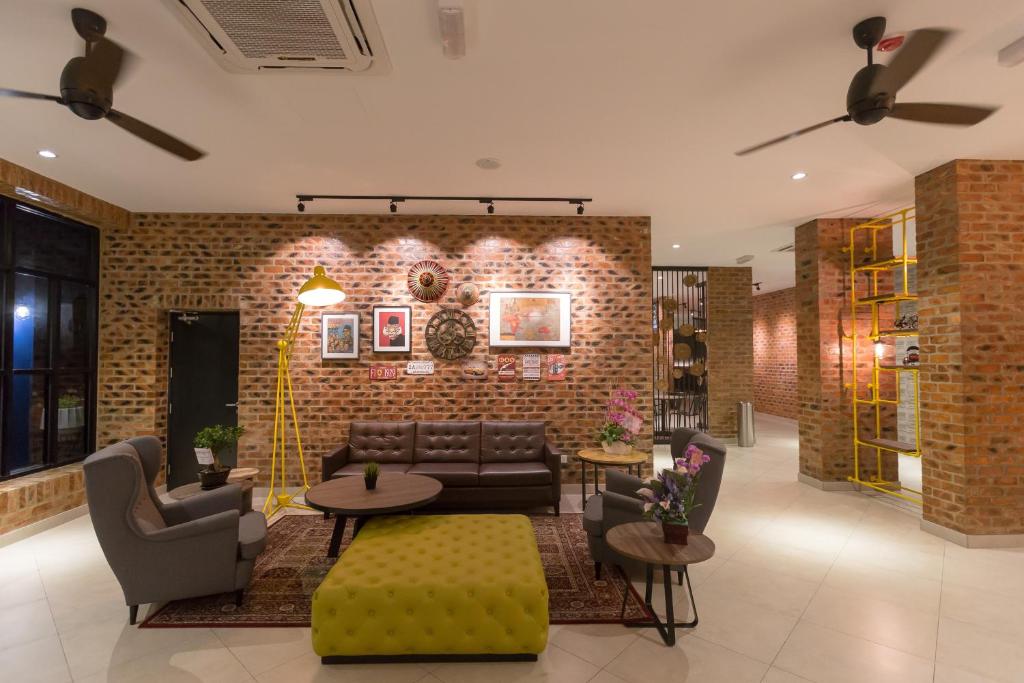 ein Wohnzimmer mit Sofas, Tischen und einer Ziegelwand in der Unterkunft Athome Boutique Hotel in Bintulu