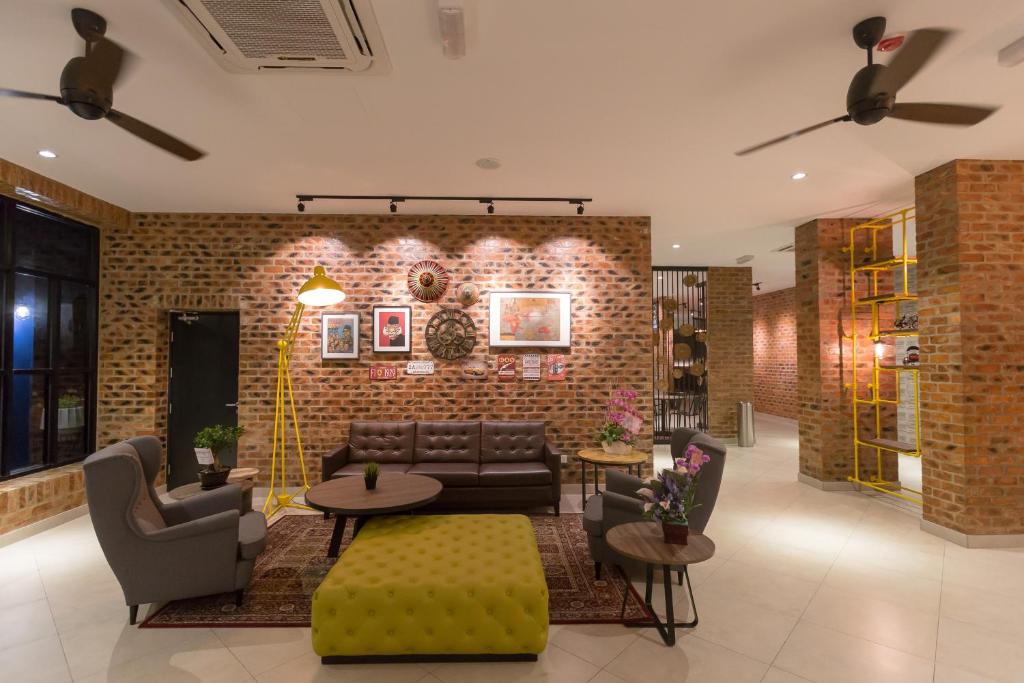 a living room with couches and tables and a brick wall at Athome Boutique Hotel in Bintulu
