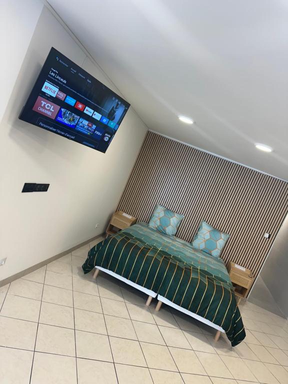 een slaapkamer met een bed en een tv aan de muur bij Là cachette in Remiremont