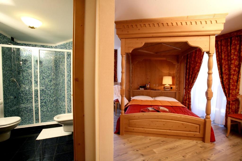 a bedroom with a canopy bed and a bathroom at Hotel Garni La Roccia in Andalo