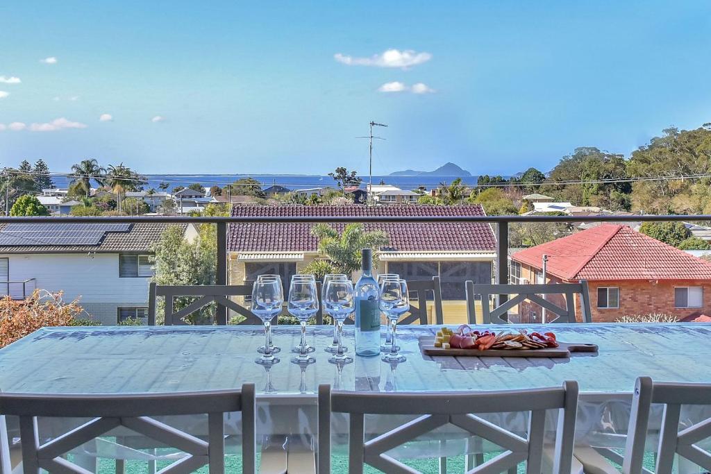 a table with wine glasses on top of a balcony at Oasis at Salamander Bay in Salamander Bay