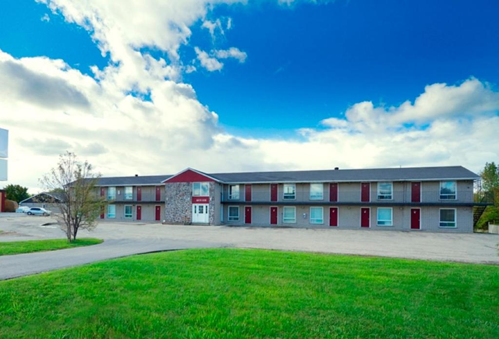 a large building with red doors and a green lawn at Save Inn in Kincardine