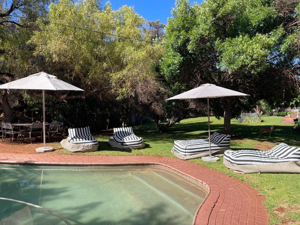 a group of chairs and umbrellas next to a pool at 7 on West in Postmasburg