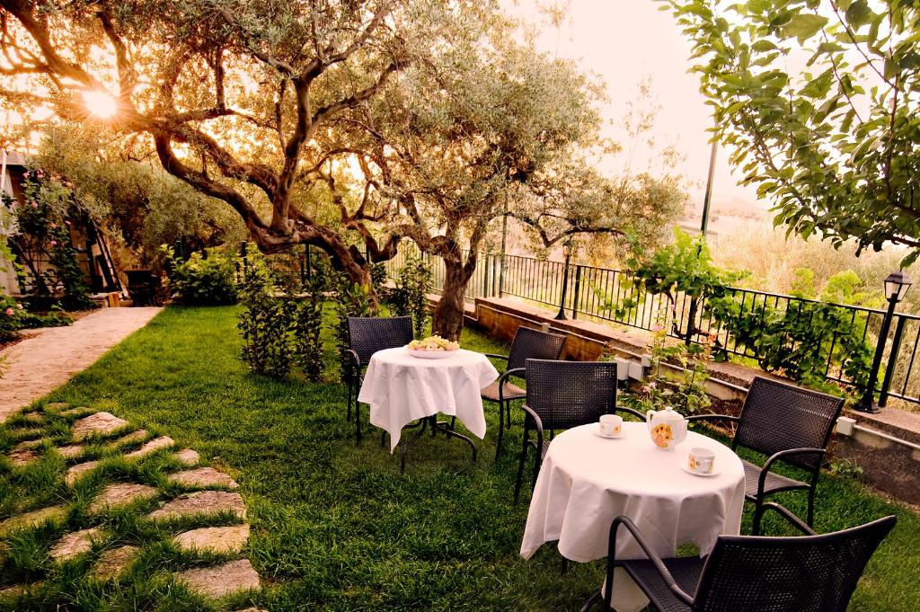 two tables and chairs on the grass in a garden at Il Grillo Holiday House in Chiaramonte Gulfi