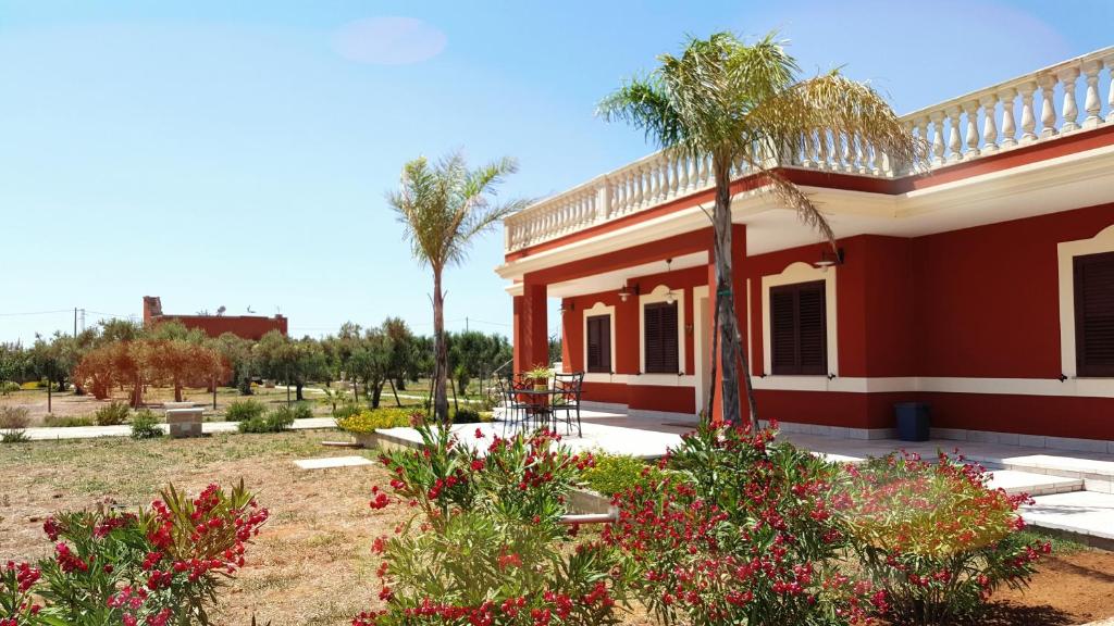 una casa con palme e fiori in un cortile di B&b Elda Salento a Tuglie