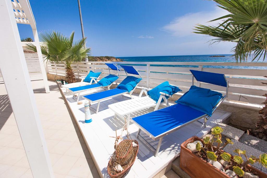 una fila de sillas azules en un balcón con vistas al océano en Villa Amateia, en Siracusa