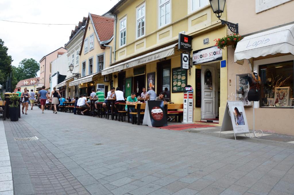 a street with people sitting at tables in front of buildings at Apartman Karolina in Zagreb