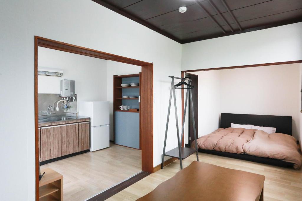 a bedroom with a bed and a kitchen at ひだまりの宿 まゆしょう in Wada