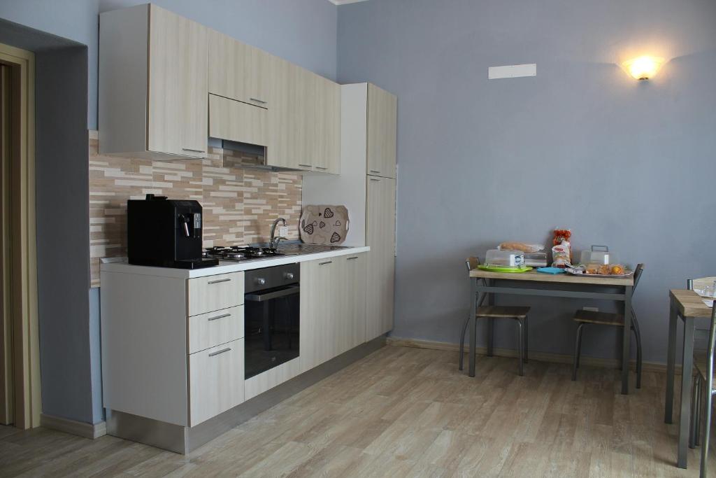 una cucina con armadi bianchi e un tavolo di B&B La Cantoniera a San Teodoro