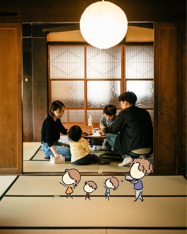 a group of people sitting around a table in a room at 古民家宿 孫八 - Mago8 in Maibara