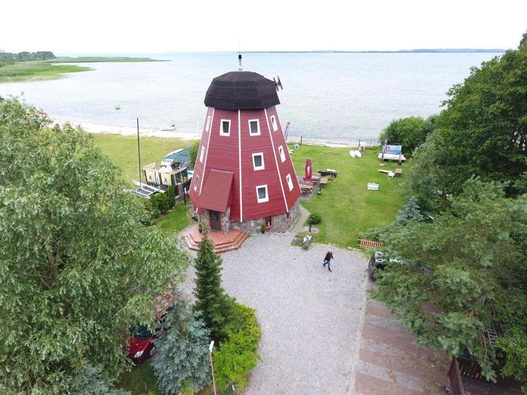 una gran casa roja con un techo negro junto al agua en Wiatrak Nowe Guty, en Nowe Guty