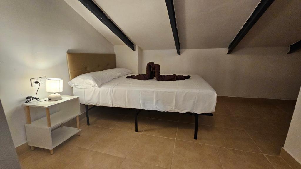 a bedroom with a bed with a white sheets and a table at Ático para 2 personas en Jaén in Jaén