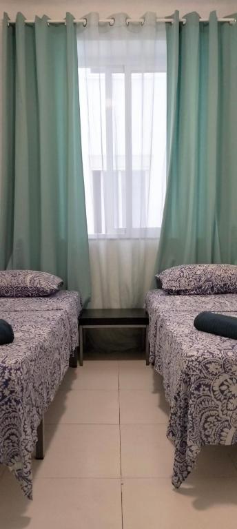 a room with two beds and a window with curtains at Pensión La Marina in Alicante