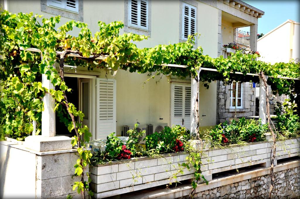 a house with a bunch of plants on a wall at Apartments Lumbarda in Lumbarda