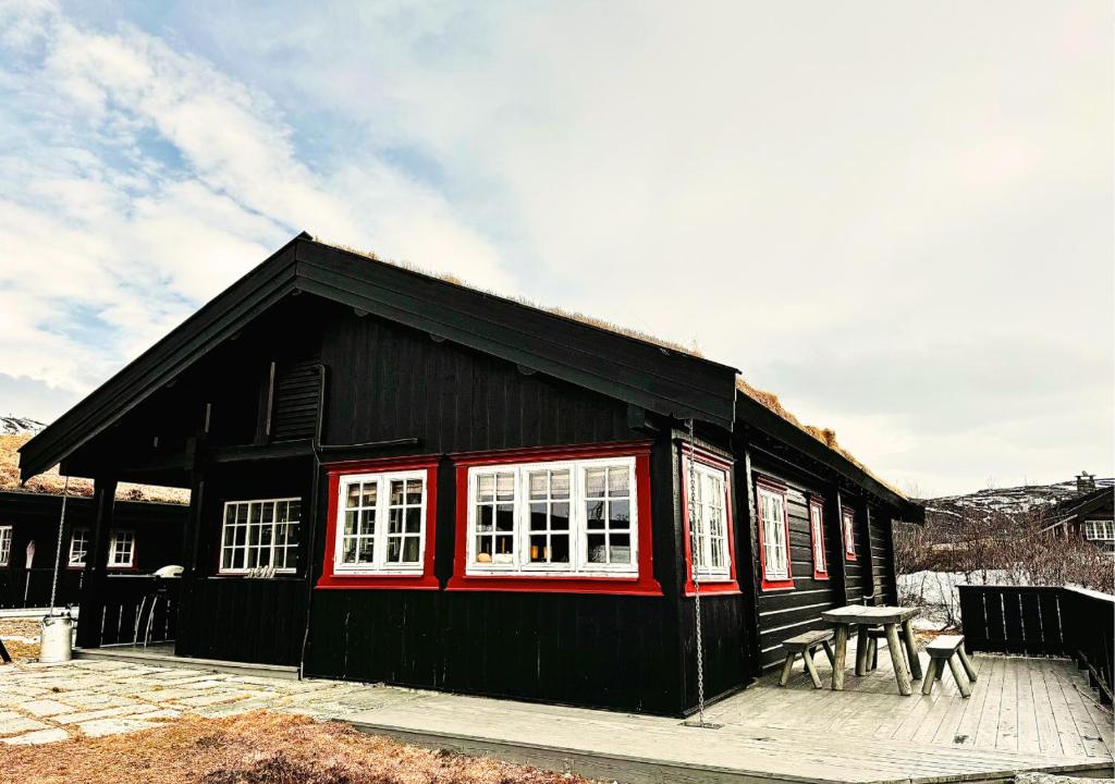 un edificio nero con finestre bianche e un tavolo da picnic di Guest favorite - 3 BR Mountain Lodge near Vøringsfossen a Maurset