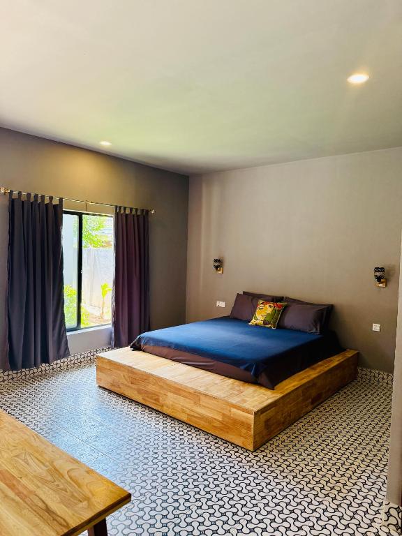 a bedroom with a large bed with a blue comforter at Angkor Piseth Retreat in Phumi Ta Phul