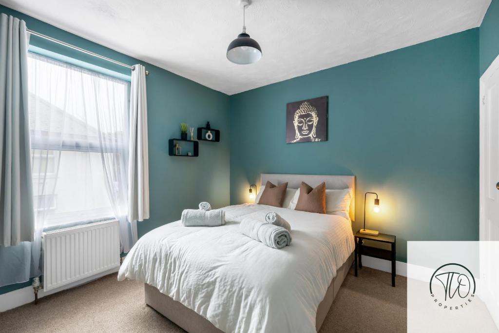 Un dormitorio con paredes azules y una cama grande. en 2BR House -Centrally Located, en Ipswich