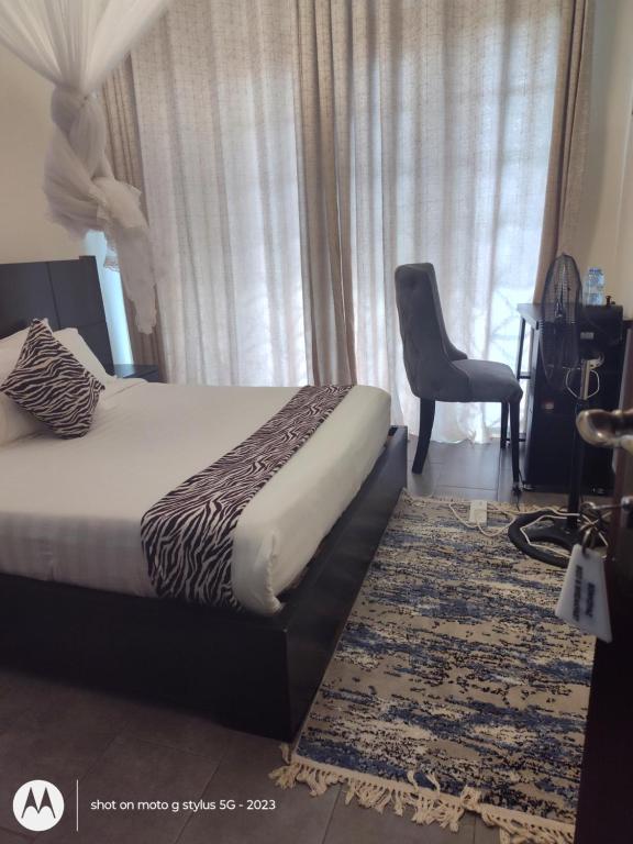 una camera da letto con un letto, una sedia e una finestra di Sonkoyaz bed and breakfast a Entebbe