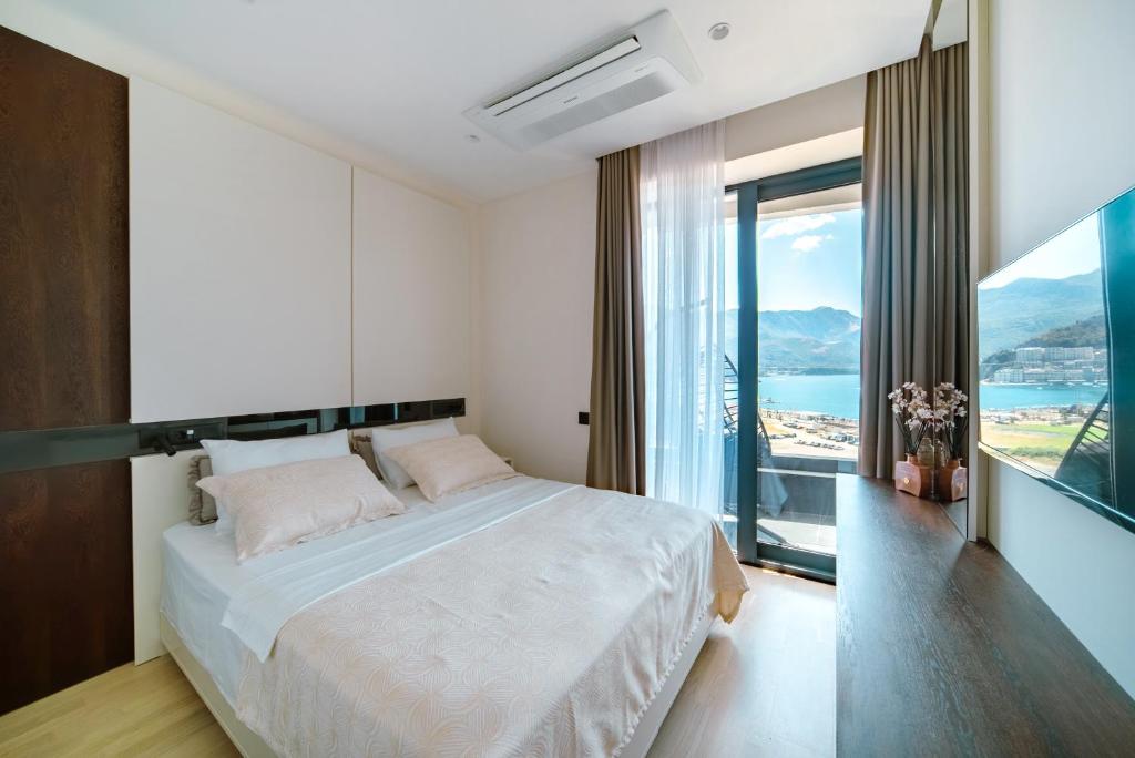 Un dormitorio con una cama grande y una ventana grande. en Bellemond Hotel & Residences, en Budva