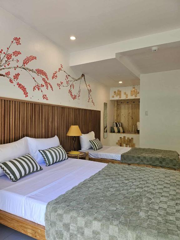 a bedroom with two beds and a mural of a tree at Kyle's Bed and Breakfast DMall Boracay in Boracay