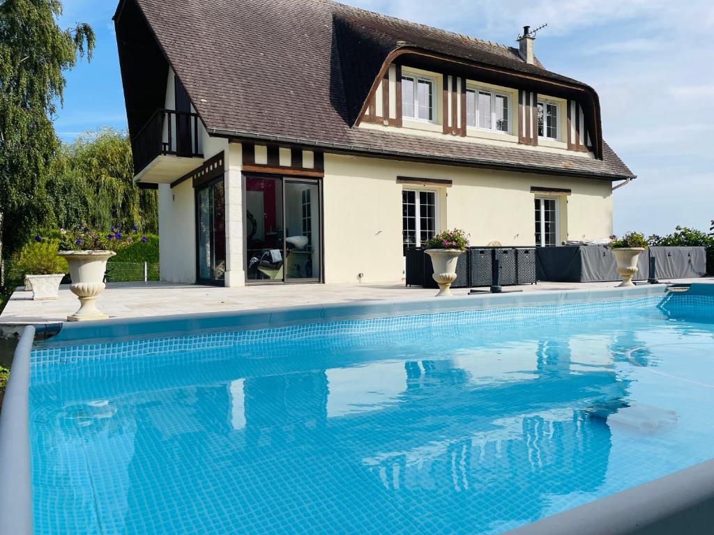 une maison avec une piscine devant une maison dans l'établissement Gîte normand climatisé avec piscine privée, à Condé-sur-Seulles