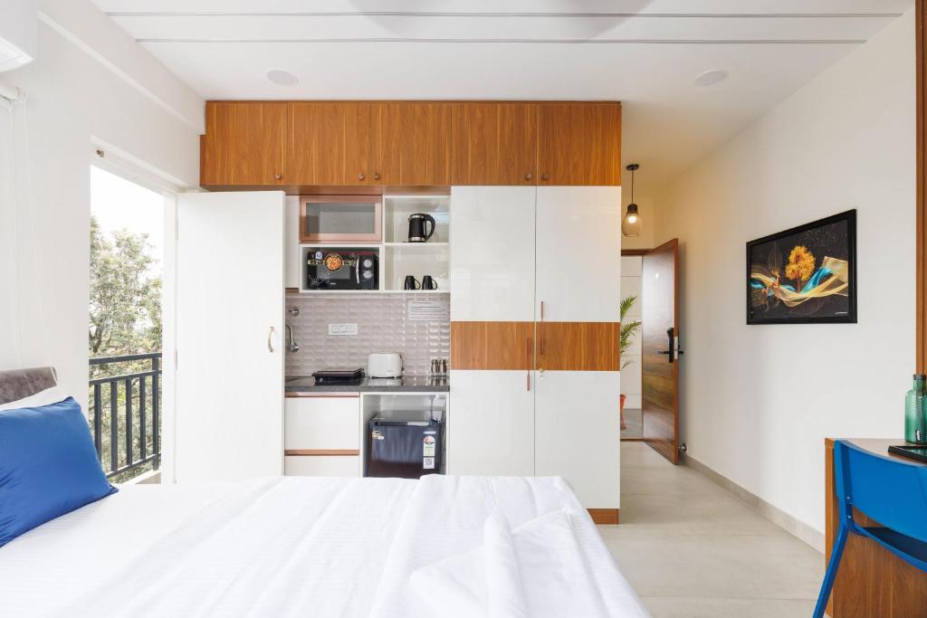 a bedroom with a white bed and a kitchen at OBS Luxury Suites - JP Nagar in Bangalore