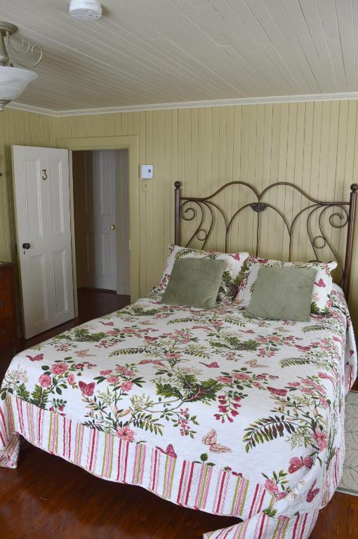 a bedroom with a large bed with a floral bedspread at La Maison entre Mer Montagnes in Cap-Chat