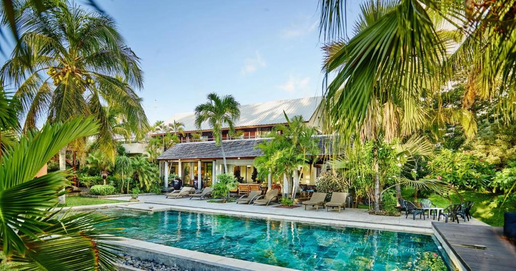 a house with a swimming pool and palm trees at Spacieuse villa avec piscine privée à Saint-Gilles les Bains 300 m² in Grand Fond