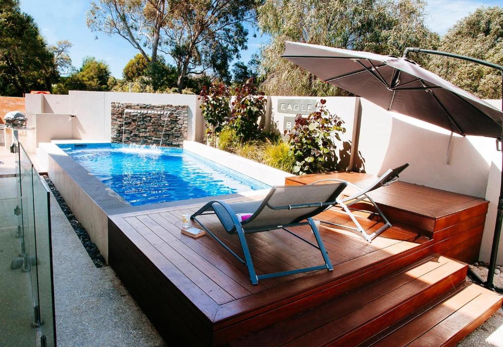 una piscina con una silla y una sombrilla en Eagle Bay Beach Retreat - Steps from the Sands, en Dunsborough