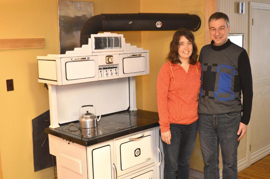 a man and a woman standing in front of a stove at La Maison entre Mer Montagnes in Cap-Chat