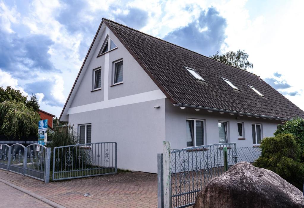 a white house with a black roof at Kajütenhus Komfort-Ferienwohnungen in Freest
