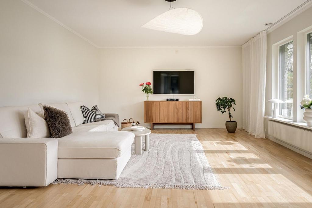 a living room with a white couch and a tv at Villa med privat läge nära Elmia in Huskvarna