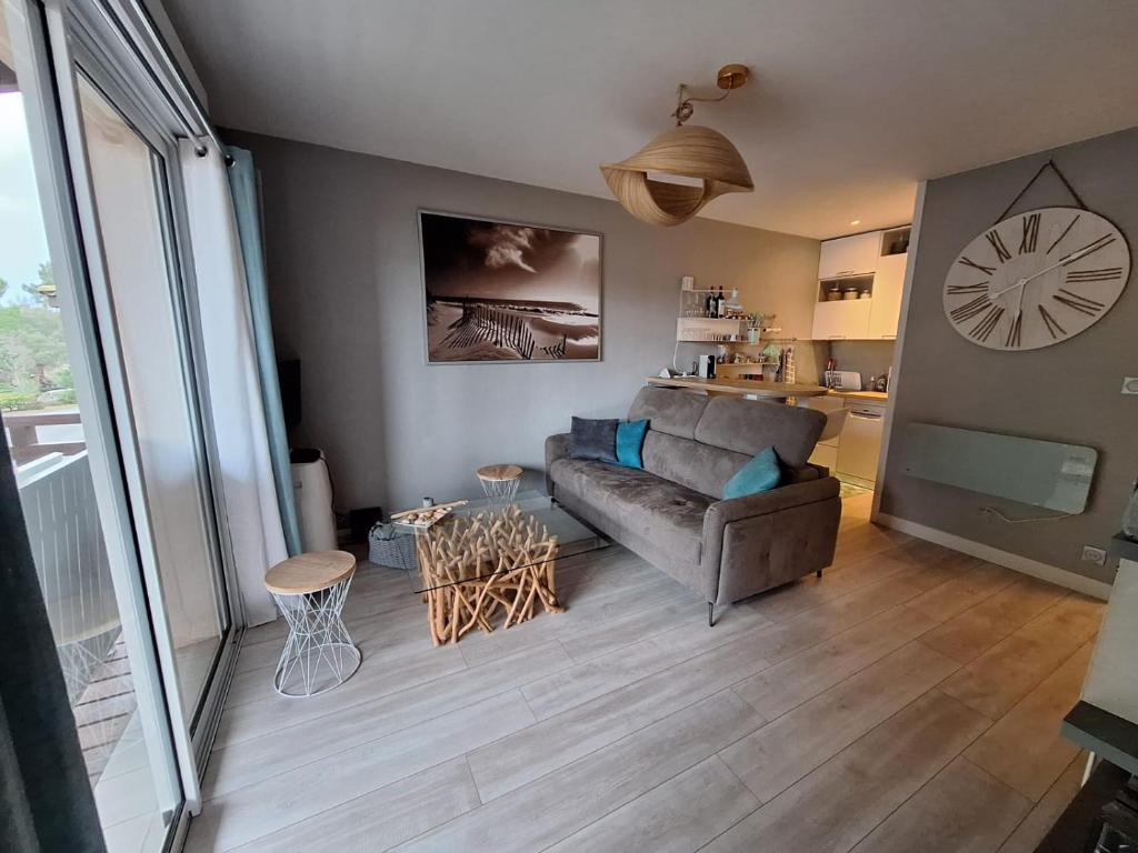 een woonkamer met een bank en een klok aan de muur bij Entre mer et golf in Moliets-et-Maa