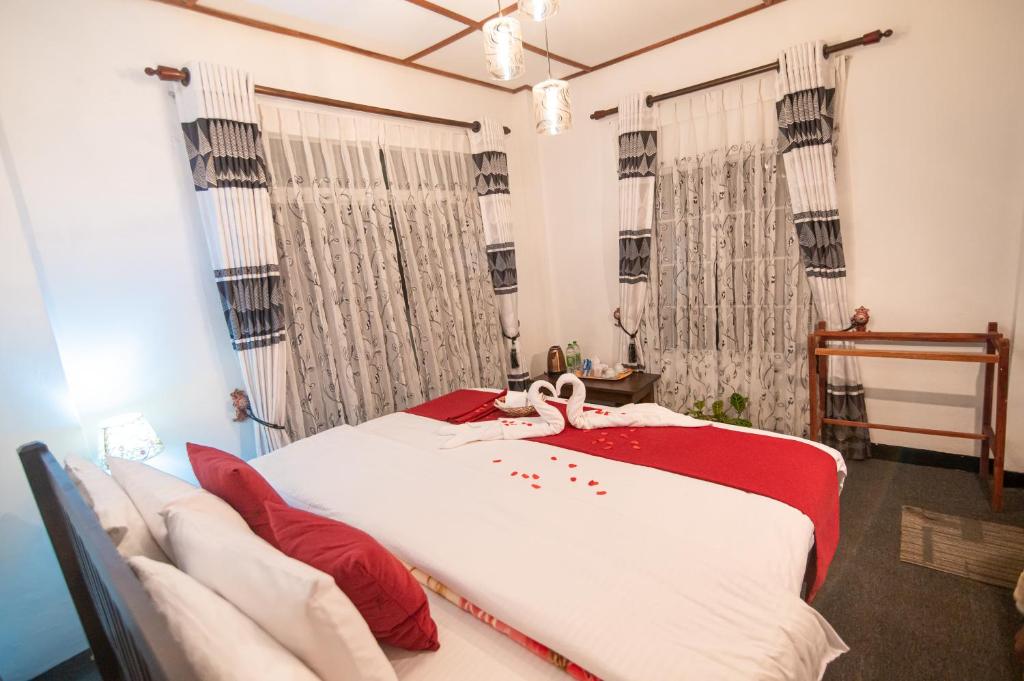 努沃勒埃利耶Top View Cottage的卧室里有一张大床，配有红色枕头