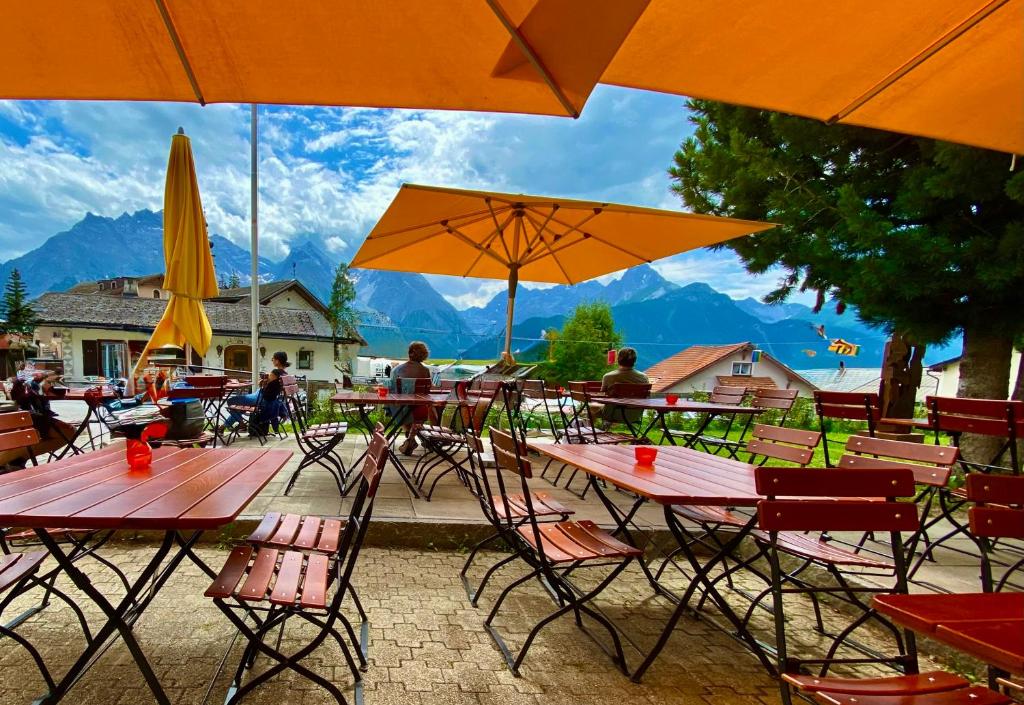 a group of tables and chairs with umbrellas at Hotel Chalamandrin in Ftan